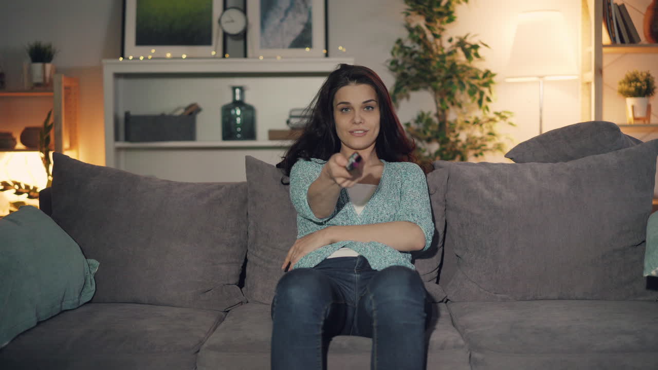 Kvinde ser tv på en sofa om aftenen