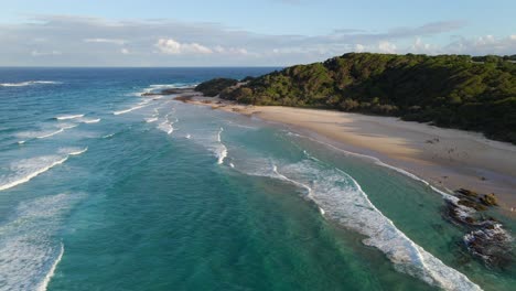 white waves rolling in the ocean along white sand beach in point lookout - deadmans headland reserve at sunset - qld, australia