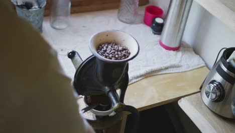 senior caucasian man grinding coffee beans in coffee mill in kitchen