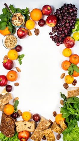 assortment of healthy fruits, nuts, and vegetables arranged on white background