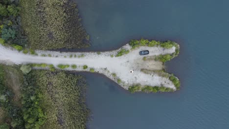 península de arena blanca en un lago con un coucle de picnic y un automóvil estacionado desde arriba - tiempo para el romance
