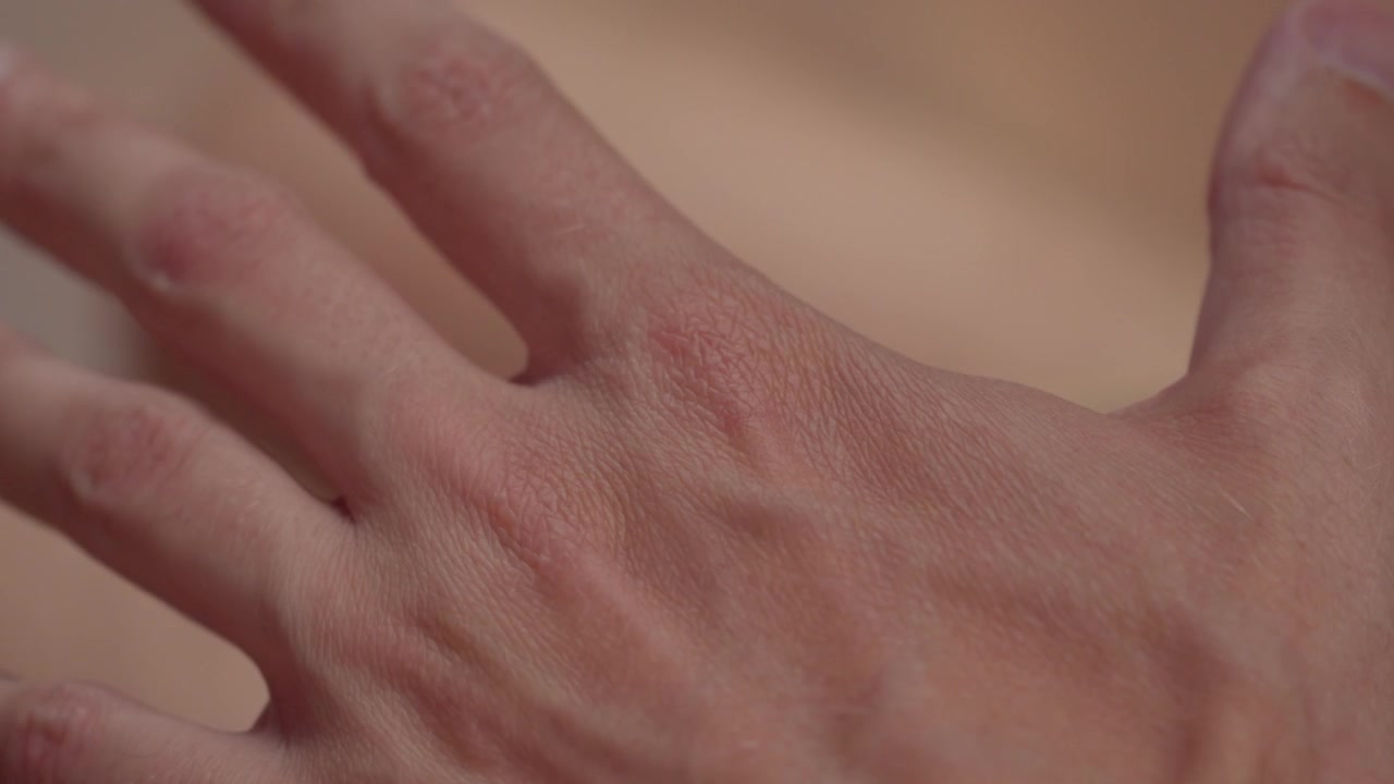 Close-up de mão masculina tensa mostrando veias e tensão muscular.