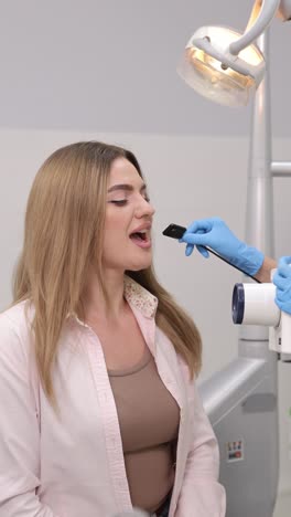 patient having dental checkup performed with advanced equipment in modern clinic environment. vertical video.