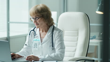 Portrait-of-Cheerful-Female-Doctor-at-Workplace-in-Medical-Office