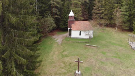 aerial revealing shot of a church in the middle of a pine forest in romania