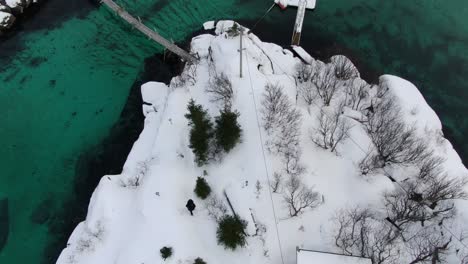 Drone-view-in-Tromso-area-in-winter-showing-a-turquoise-crystal-clear-sea-surrounding-an-island-in-Norway-top-view