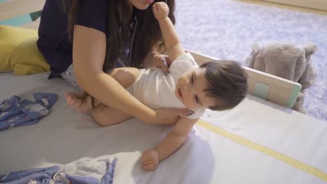 a mother lifting her baby from her bed. happy and cute baby.