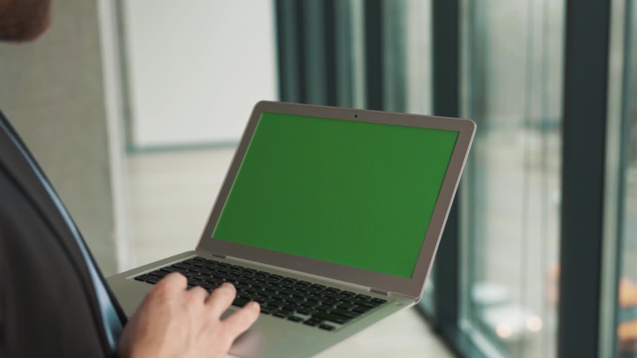 Close-up of a laptop screen with a chromakey in the hands of a man on the background of a panoramic window