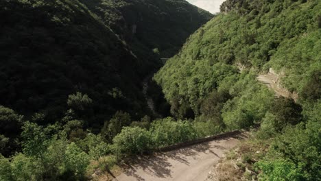 Forward-aerial-view-of-a-waterless-riverbed-within-mountains