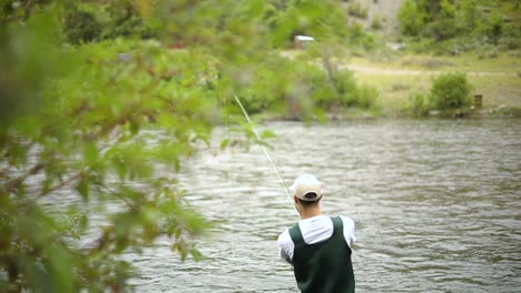 Slow-Motion-Shot-of-a-Caucasian-male-fisherman-casting-his-hook-while-Fly-Fishing