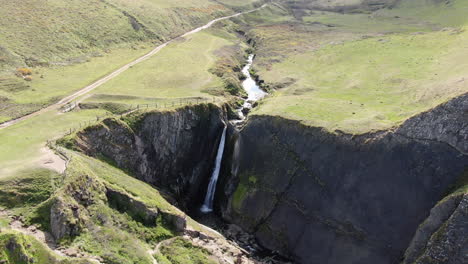 aerial shot of spekes mill mouth waterfall, in devon on the uk coast