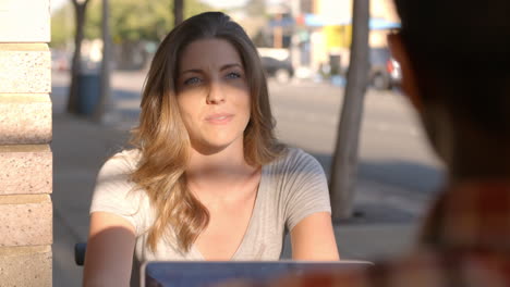 Couple-talking-at-a-table-outside-a-coffee-shop