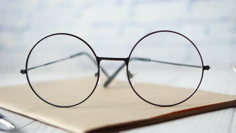 notepad, eyeglass and a pencil on wooden table