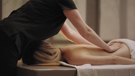 chiropractor is massaging back of young female patient in massage parlor curing and preventing scoliosis
