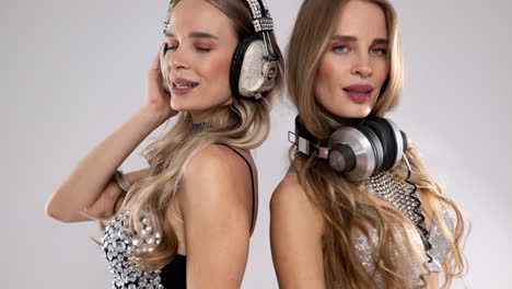 identical twin female djs in sparkling silver costume dancing behind vintage gramophones