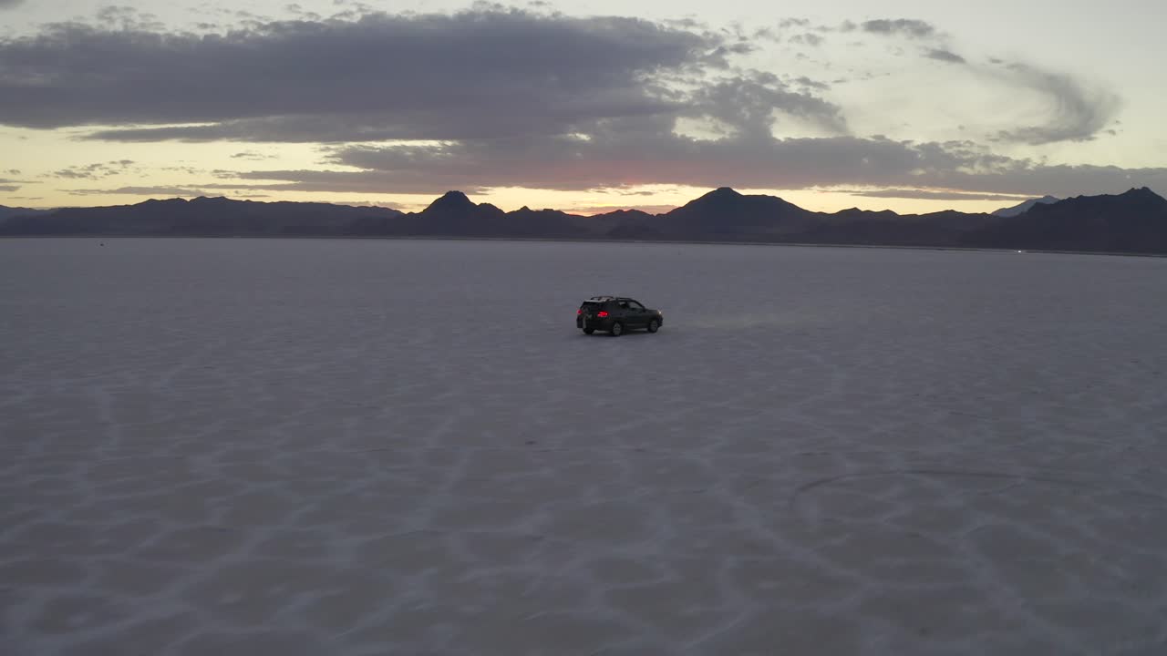SUV in movimento all'ora blu, con i fari che illuminano il percorso alle Bonneville Salt Flats.
