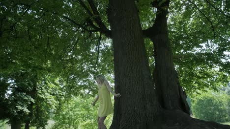 woman in yellow dress dancing by tree in summer park