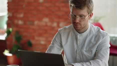 Schöner-Mann-Tippt-Nachrichten-Und-Sendet-Online-Chat-Im-Laptop,-Sitzt-Und-Arbeitet-Im-Café