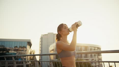 happy girl in a sports summer uniform drinks water from a special sports bottle in the morning