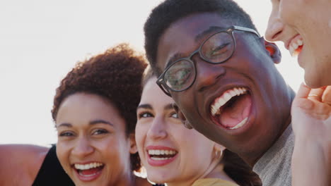 cabeza y hombros retrato de amigos jóvenes sonrientes al aire libre juntos contra el sol abrasador