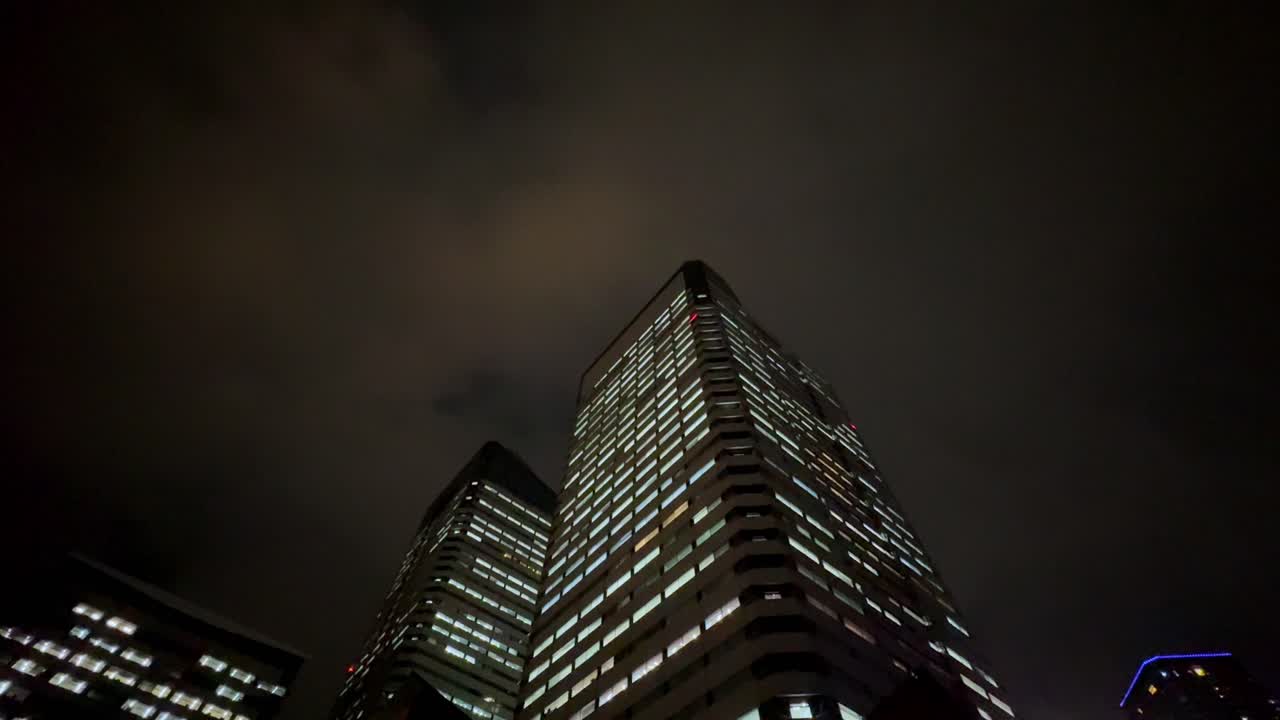 vista nocturna tormentosa de rascacielos iluminados en el distrito de harumi de tokio con nubes y truenos dramáticos