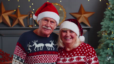 Smiling-married-senior-couple-grandparents-man-woman-in-living-room-celebrating-Christmas-together