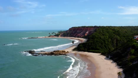 Amazingly-gorgeous-aerial-drone-left-trucking-shot-of-the-tropical-beach-of-Tabatinga-with-large-colorful-cliffs,-green-water,-and-beautiful-sand-near-Joao-Pessoa,-Brazil-on-a-warm-sunny-summer-day