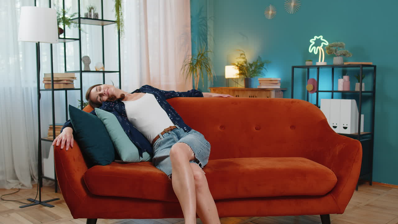 편안한 가정 소파에 앉아 휴식을 취하고 낮잠을 자고 편안한 옷을 입은 피곤한 젊은 여성