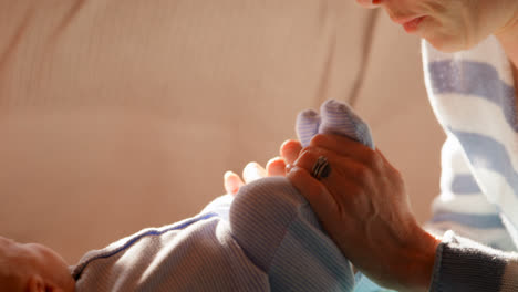 Mother-playing-with-her-baby-boy-feet-in-living-room-4k