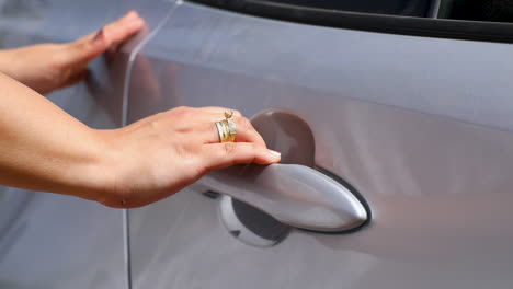 A-woman-opens-a-car-door-in-the-street---close-up