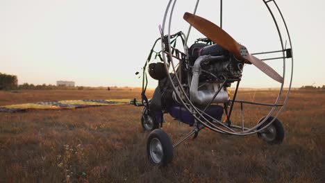 el parapente de motor se encuentra en el aeropuerto en los rayos de la luz del atardecer. la cámara se mueve a lo largo de la órbita