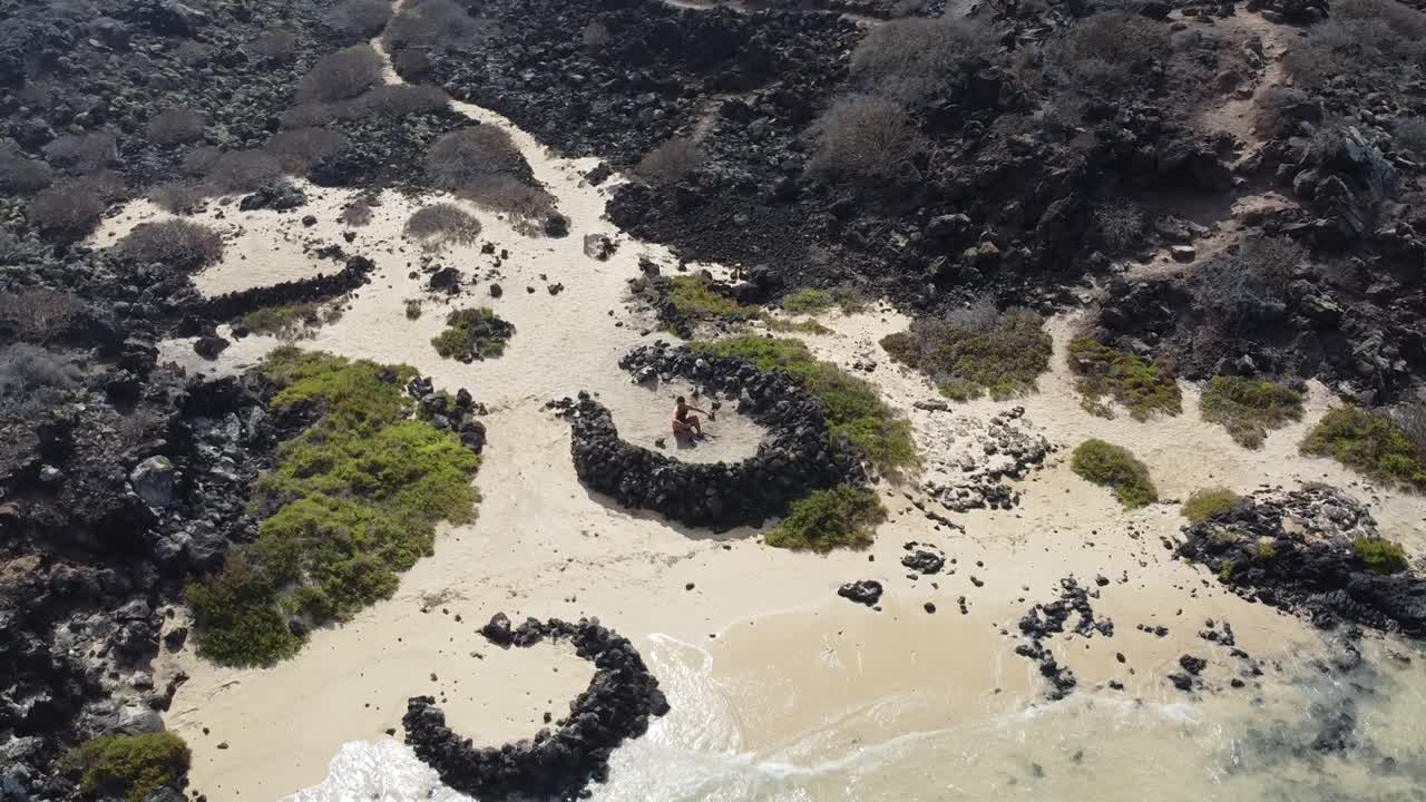 imágenes aéreas de drones de un chico relajándose en una bonita playa con aguas turquesas en lanzarote, islas canarias