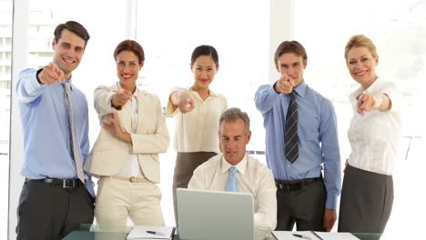 equipo de negocios hablando frente a la computadora portátil y luego apuntando a la cámara