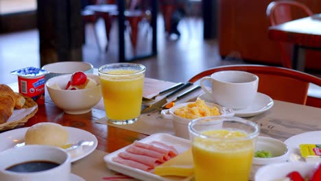 nutritious breakfast with fruits, cheese, ham and egg, steam is seen rising from a cup of hot coffee