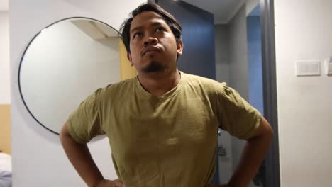 southeast asian man open wardrobe and confused choosing outfit