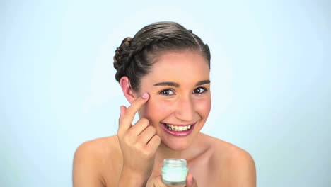 mujer joven aplicando crema en su cara