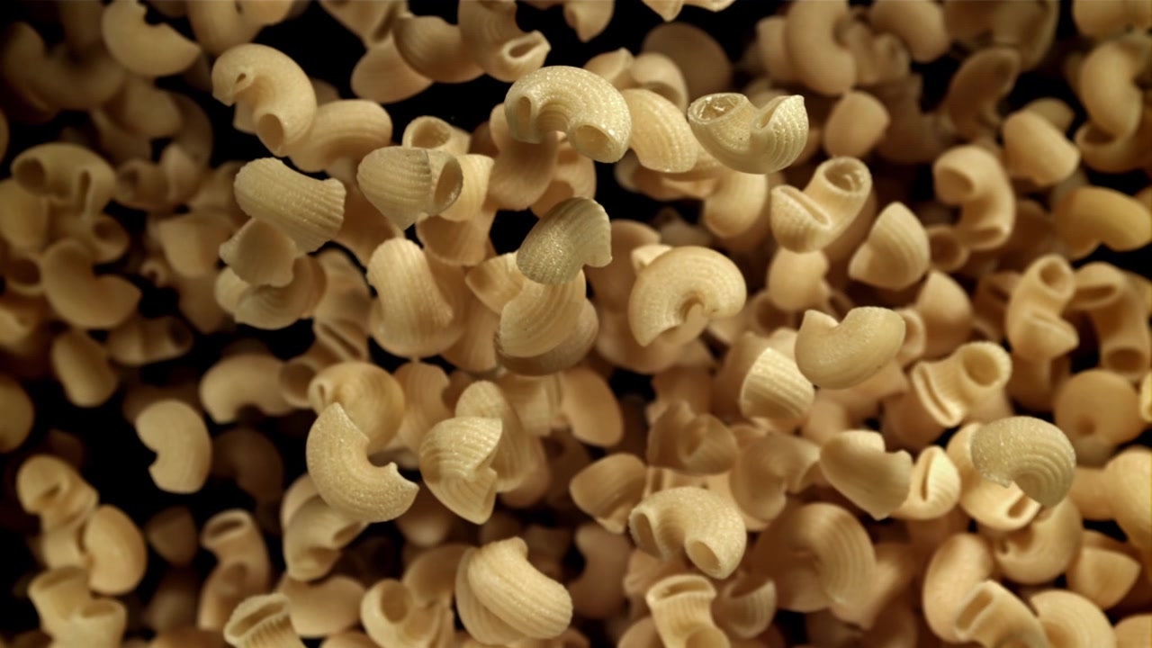 Maccheroni crudi in caduta al rallentatore su sfondo scuro