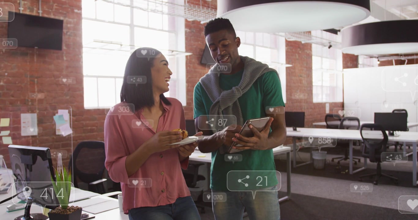 Man turning tablet to colleague and tapping, woman holding pastry and tracking social HUD metrics