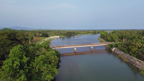 Impresionante-Fotografía-Aérea-Con-Dron-Del-Río-Y-El-Puente-Que-Conectan-Las-Aldeas-De-La-Selva-Tropical-En-Virac,-Catanduanes