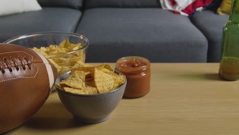 salón en casa después de ver un partido de fútbol americano en la televisión con bebidas, bocadillos y pelota 2