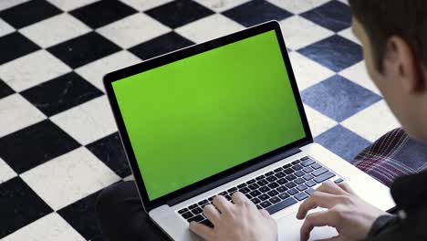 person working on a laptop with a green screen