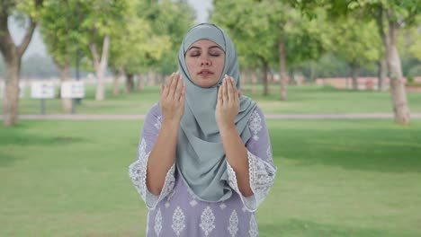 happy muslim woman praying to god in park