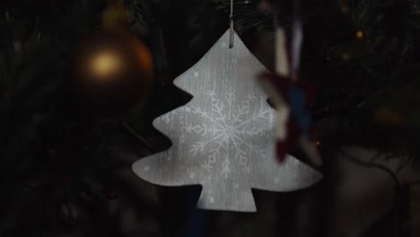 Christmas-lights-twinkling,-ornament-hanging-on-tree-comes-into-focus