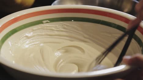 a hand mixing a pancake batter in a large bowl - close up shot