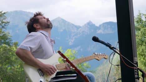 guitar player emotional feeling it below mountains alps slovenia