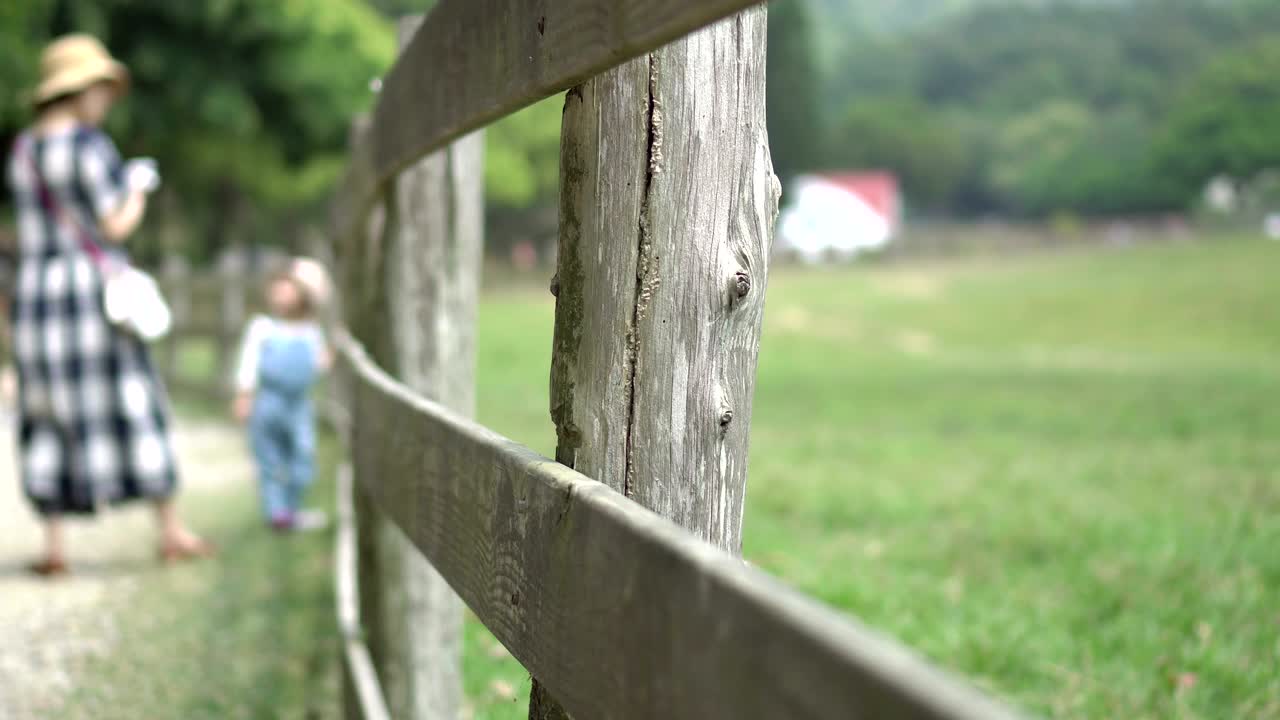 엄마와 딸은 랜치의 나무 울타리 근처에 있습니다.