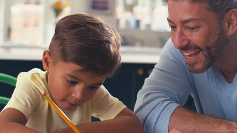 Close-Up-Of-Mature-Father-At-Home-In-Kitchen-Helping-Son-With-Homework