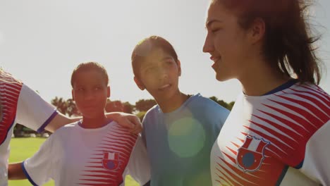 Female-soccer-player-encouraging-her-team-while-standing-arm-to-arm-on-soccer-field.-4k