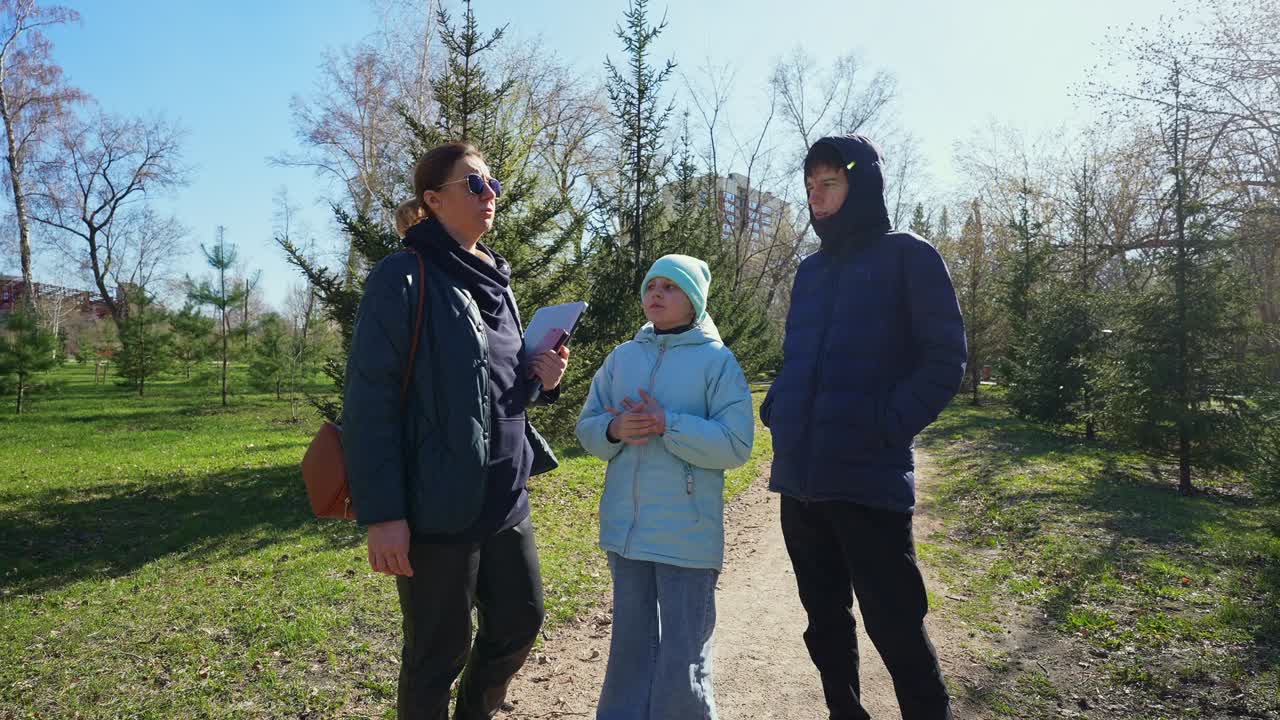 Donna e due bambini che parlano in un parco soleggiato