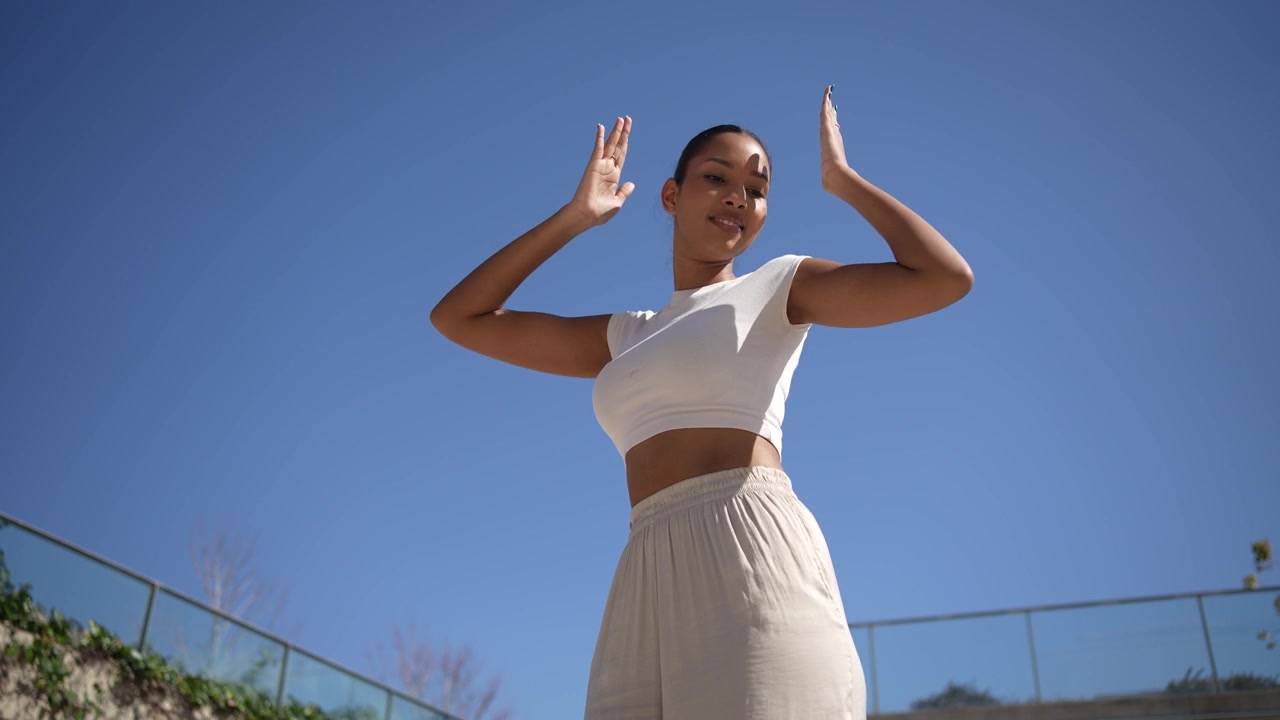 A joyful woman dancing happily under a clear beautiful blue sky filled with sunshine